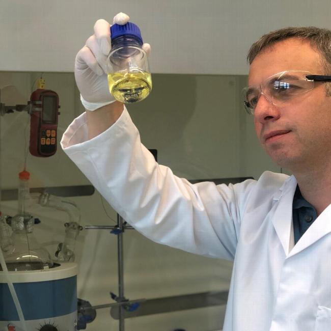 Researcher at refiniti holding a bottle of pyrolysis oil